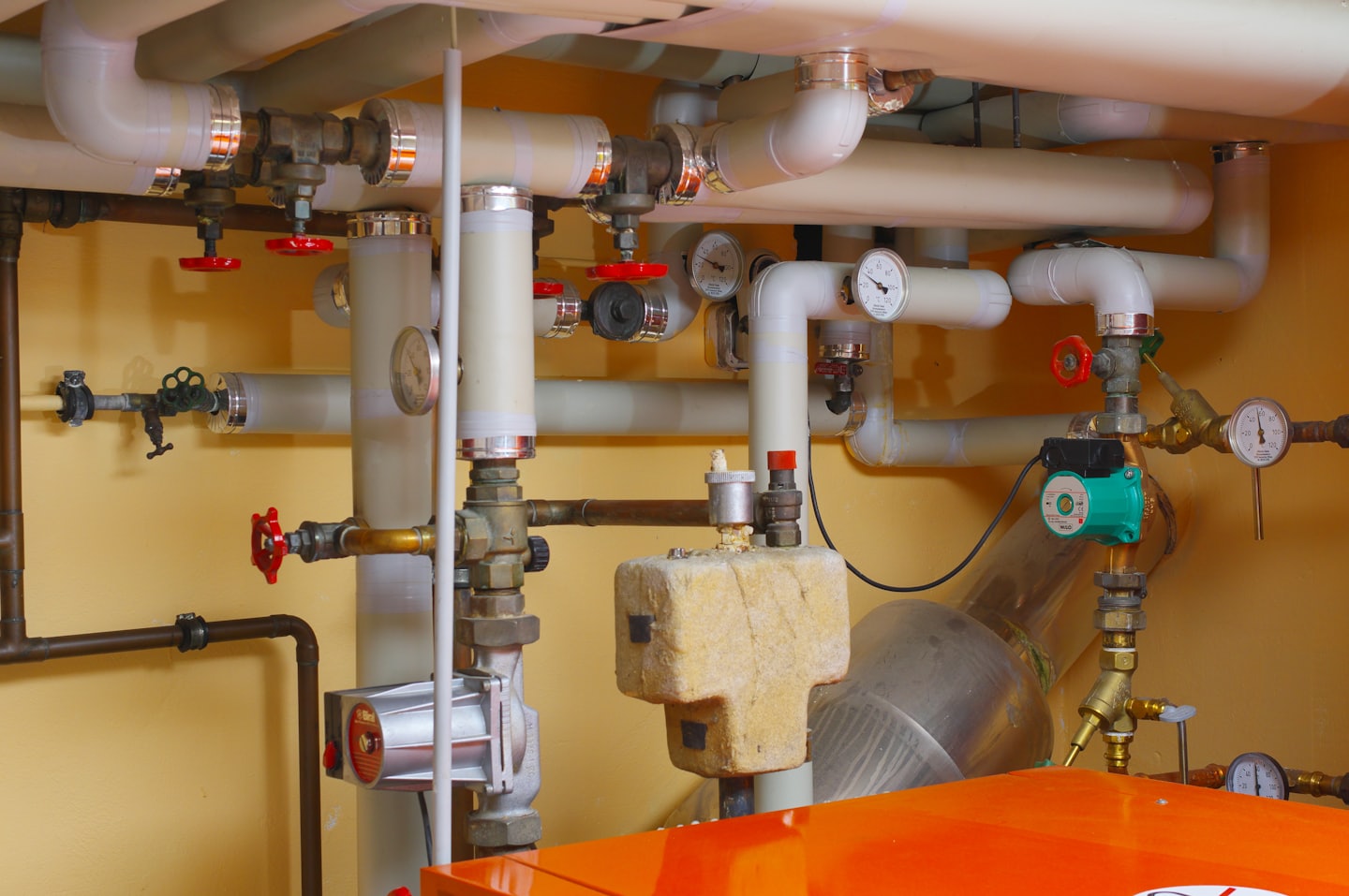 Network of pipes, valves, and gauges in a utility room.